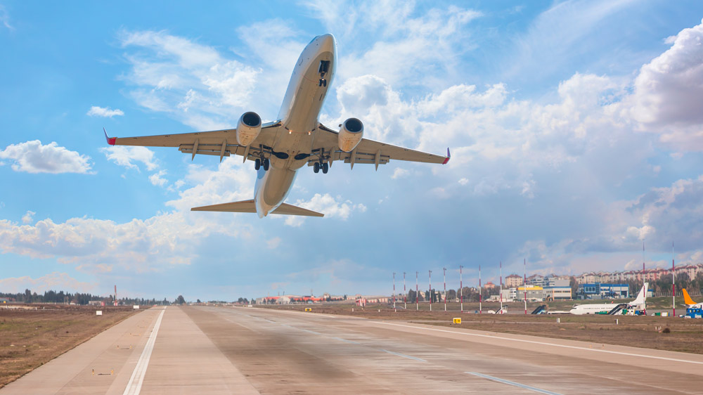 Adobe stock photography of an airplane taking off from an airport runway during the day.
