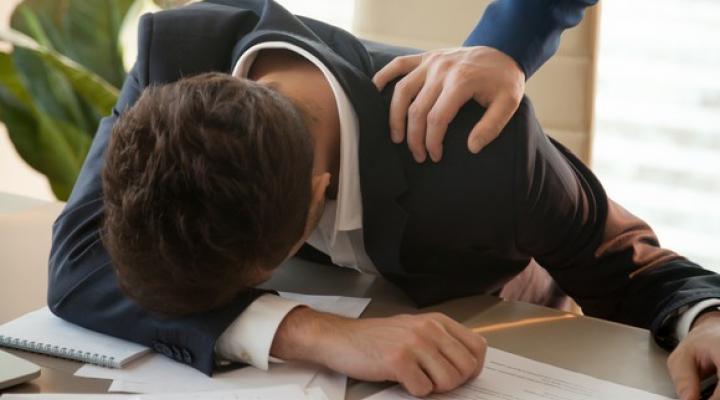 A person has his head on a desk.