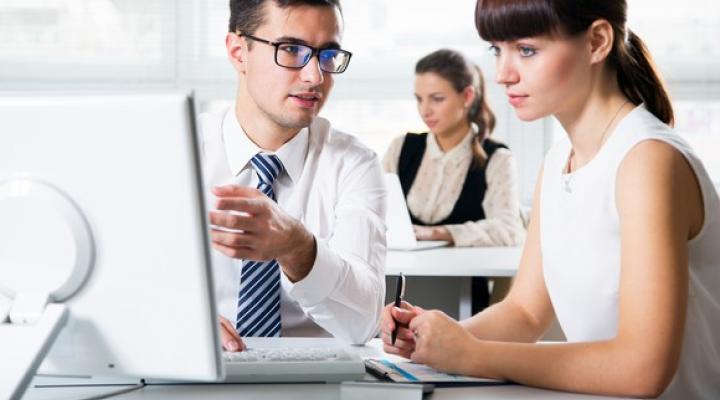 Man showing woman something on his computer screen